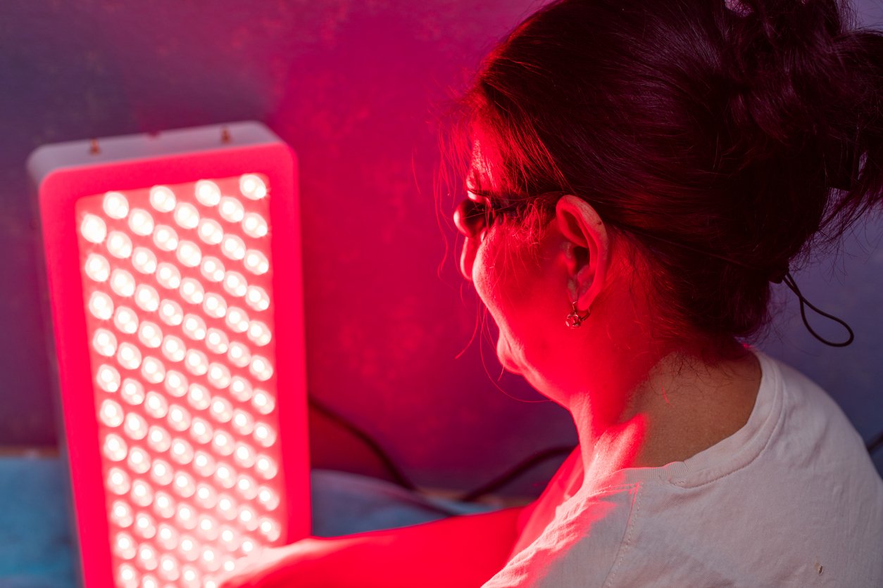 Senior woman doing Red Light Therapy Session with Panel