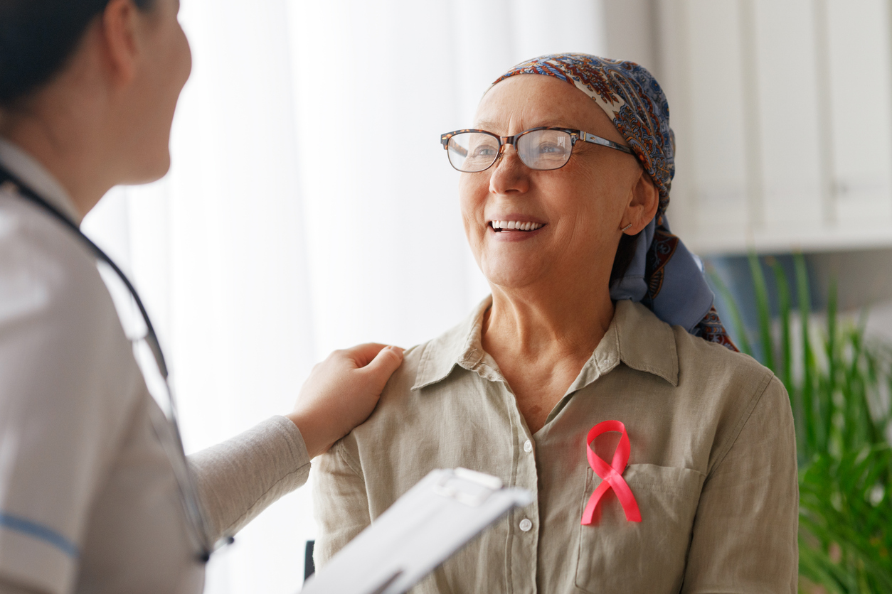 Pink ribbon for breast cancer awareness. Female patient listening to doctor in medical office. Support people living with tumor illness.