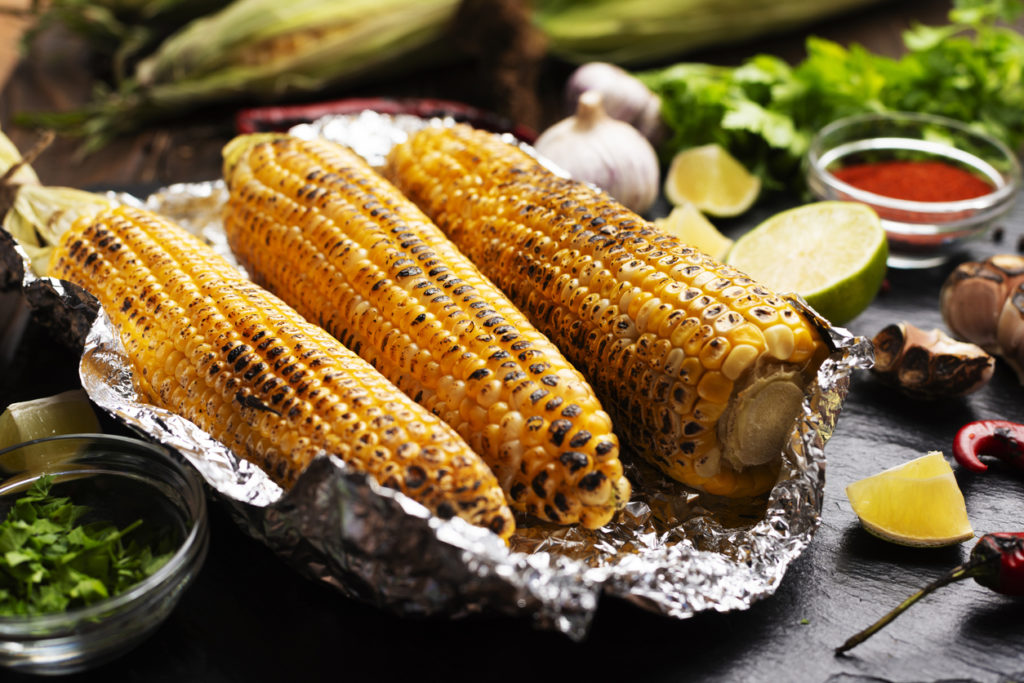 Grilled corn on the cob in tin foil on kitchen table
