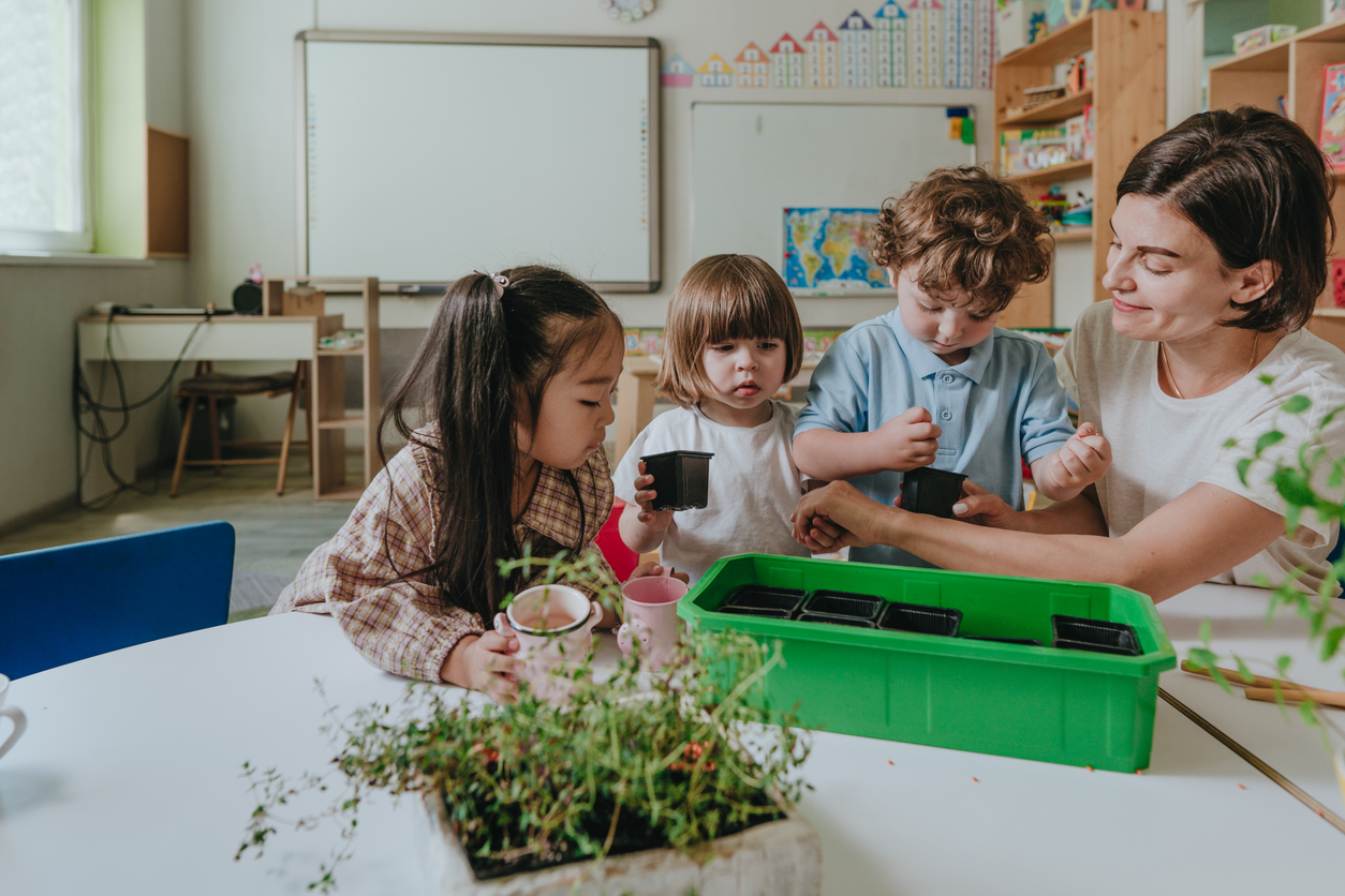 Kids in a kindergarten class learning how to plant things with their teacher