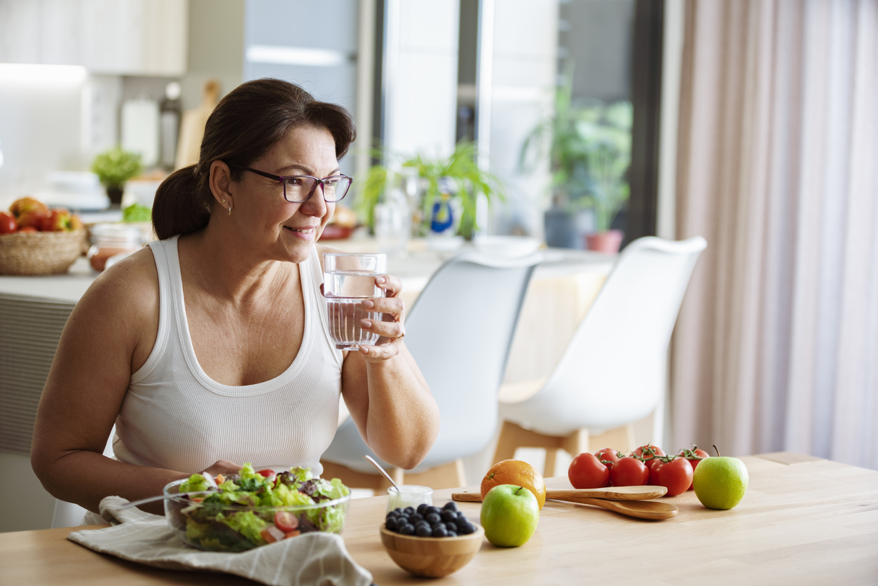 Healthy eating concept. Woman drinkig water while having a healthy meal of salad and fruits. High resolution 42Mp indoors digital capture taken with Sony A7rII and Canon EF 70-200mm f/2.8L IS II USM Telephoto Zoom Lens