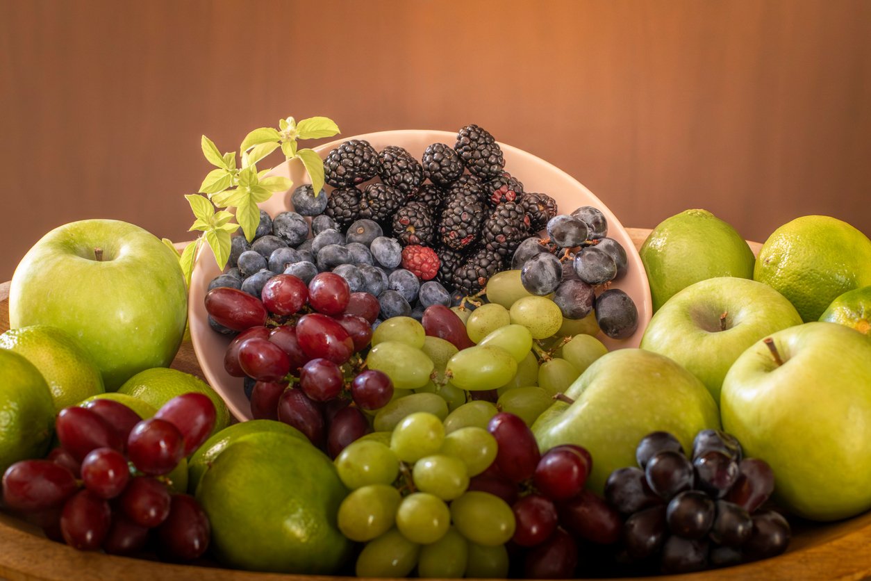 A variety of fruits, including grapes, apples, blackberries, limes and blueberries, arranged in a fruit bowl.