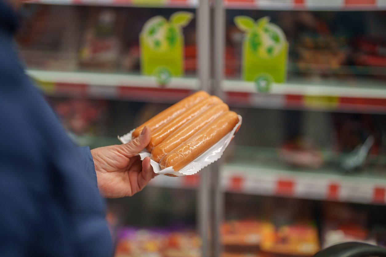 Hands holding plant-based hot dogs in packaging
