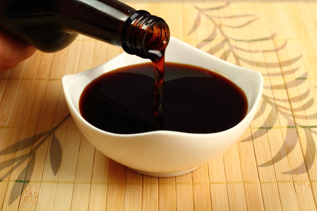 Pouring soy sauce into a white bowl