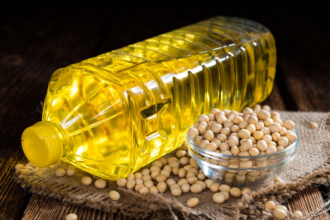 bottle of soybean oil next to soybeans