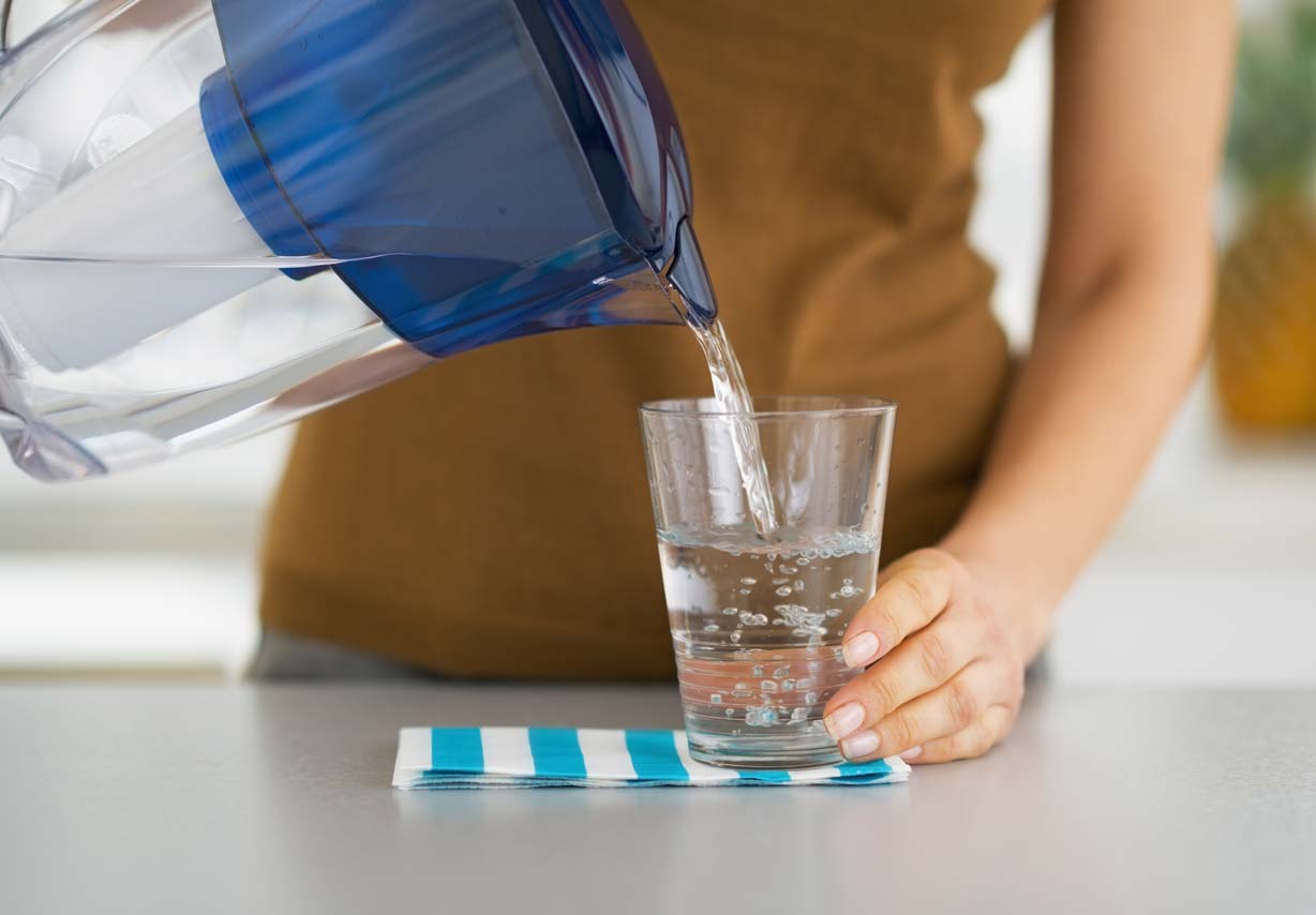 pouring water into glass from pitcher style water treatment system