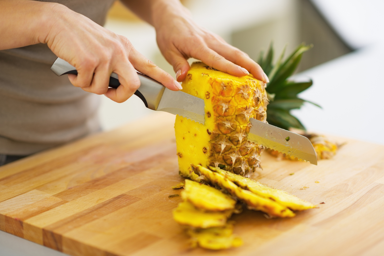 closeup on woman cutting pineapple