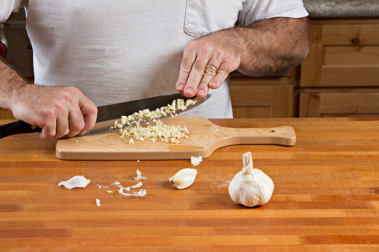 A close up shot of a cook chopping garlic.