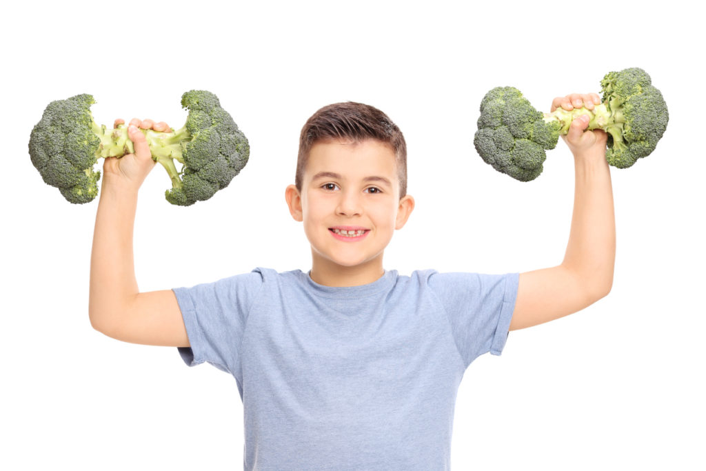 Young boy lifting broccoli like weights