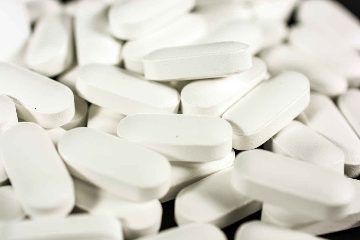 Many large white pill capsules close-up background