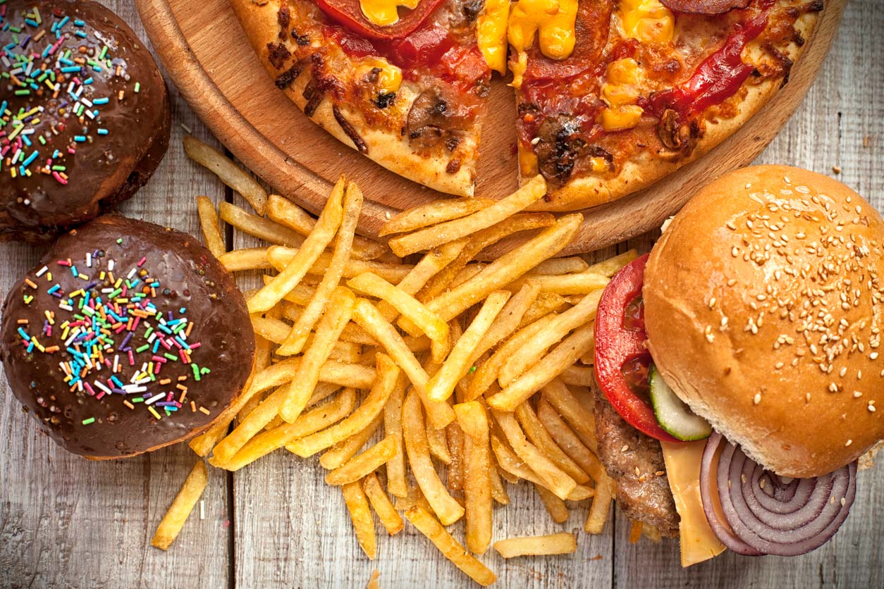 Pizza, burger, fries, and cupcakes on table: Unhealthy foods for weight gain