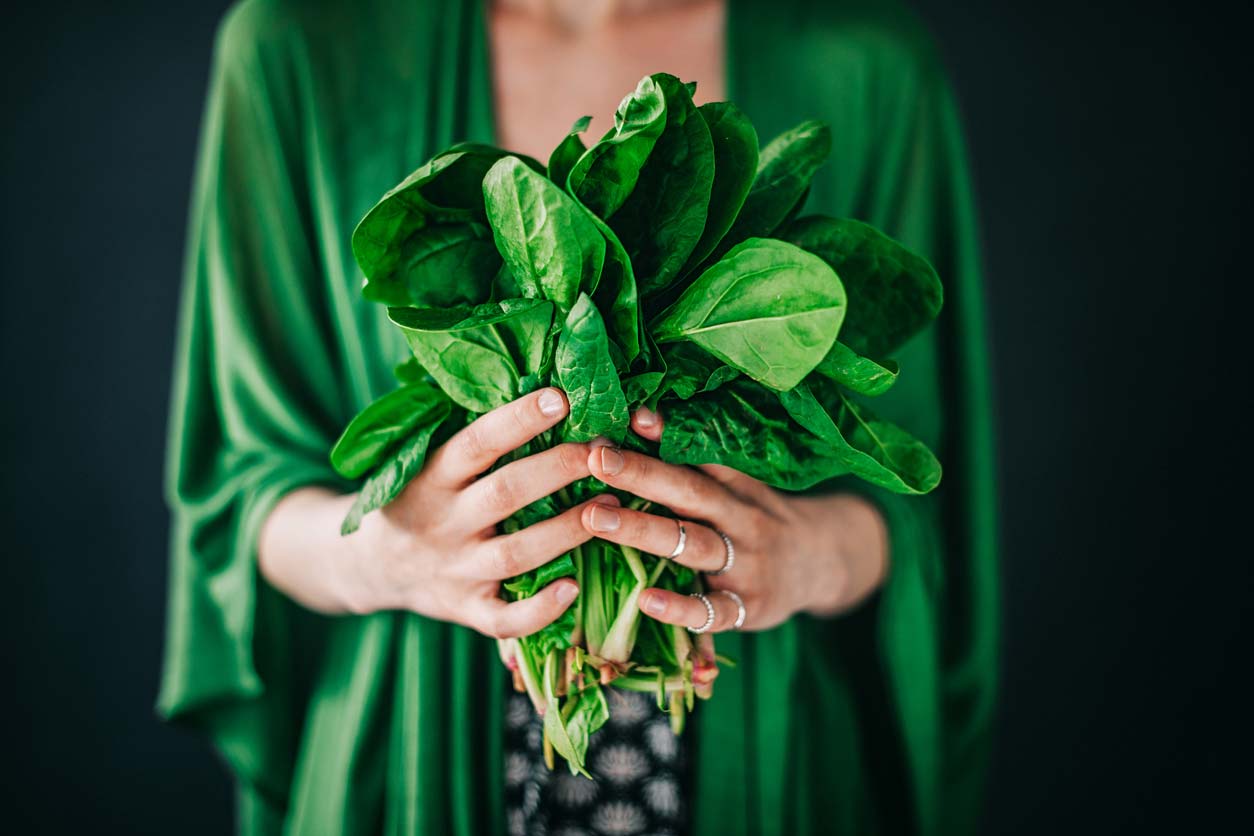 woman in green shirt holding freshly picked spinach