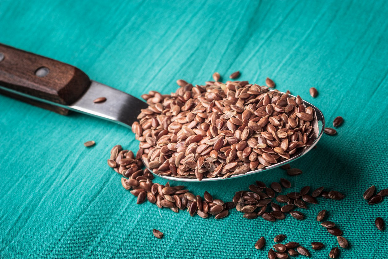 Healthy food. Flax seeds linseed on kitchen spoon linen green color background