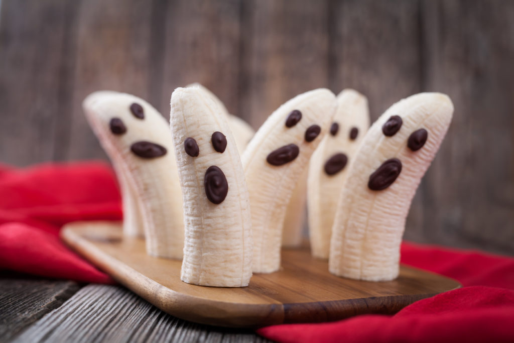 Peeled bananas that look like ghosts with chocolate chip faces