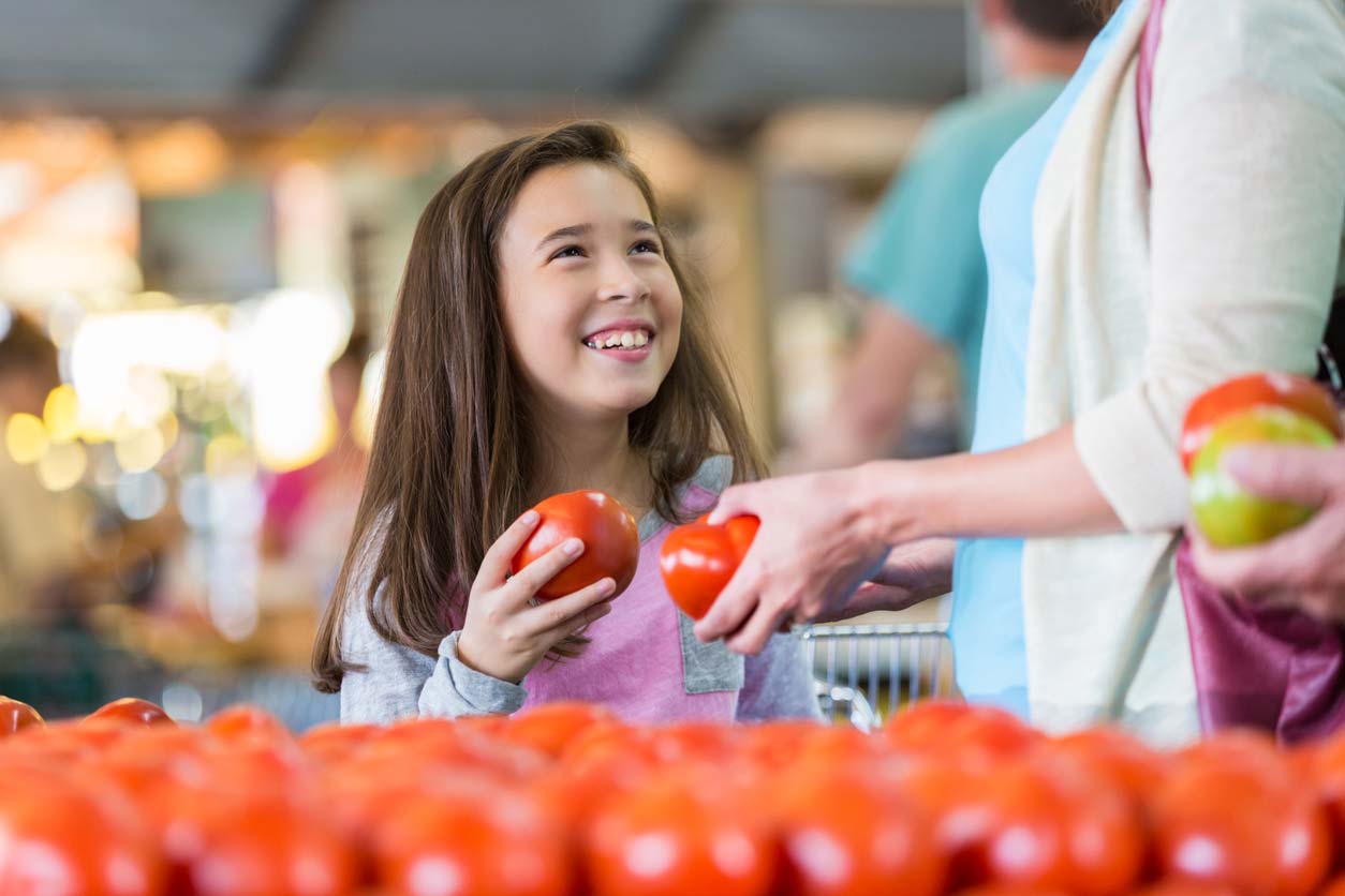 little girl shopping for produce with mother