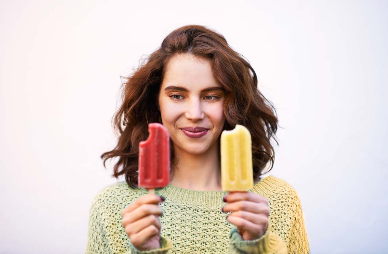 woman holding and comparing two popsicle brands