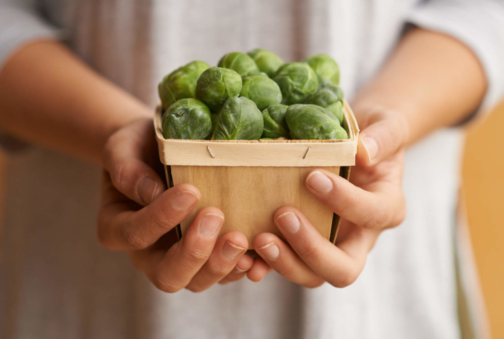 Hands holding a container of Brussels sprouts