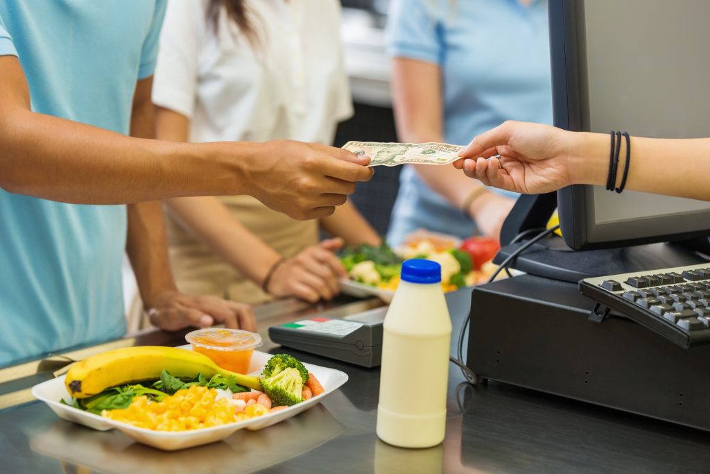 Student paying for school lunch with cash in cafeteria