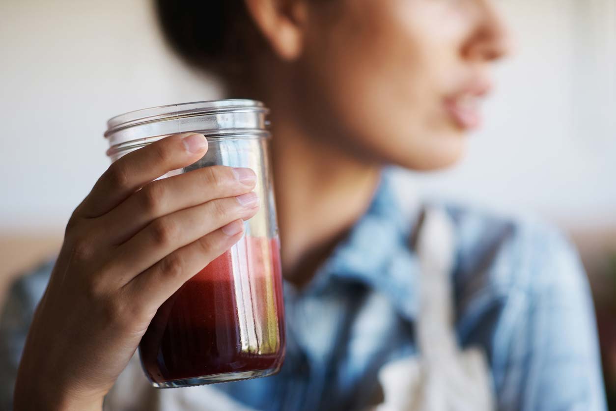 closeup of woman holding jar with red smoothie