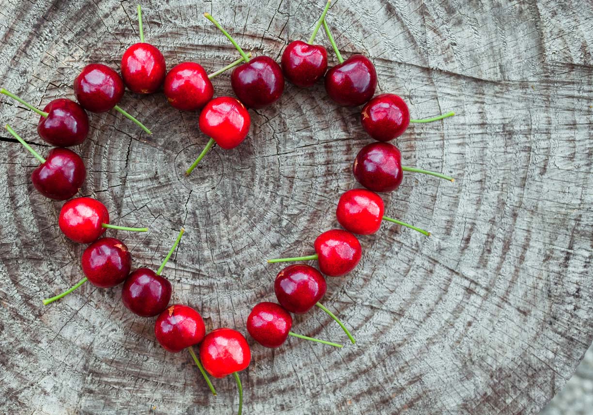 cherries in shape of heart on wooden surface