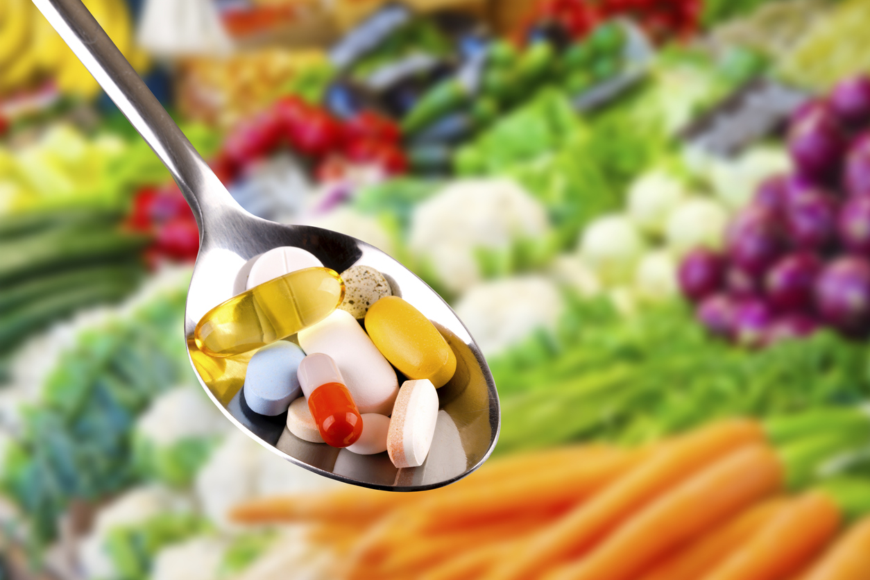 spoon with pills dietary supplements on vegetables background