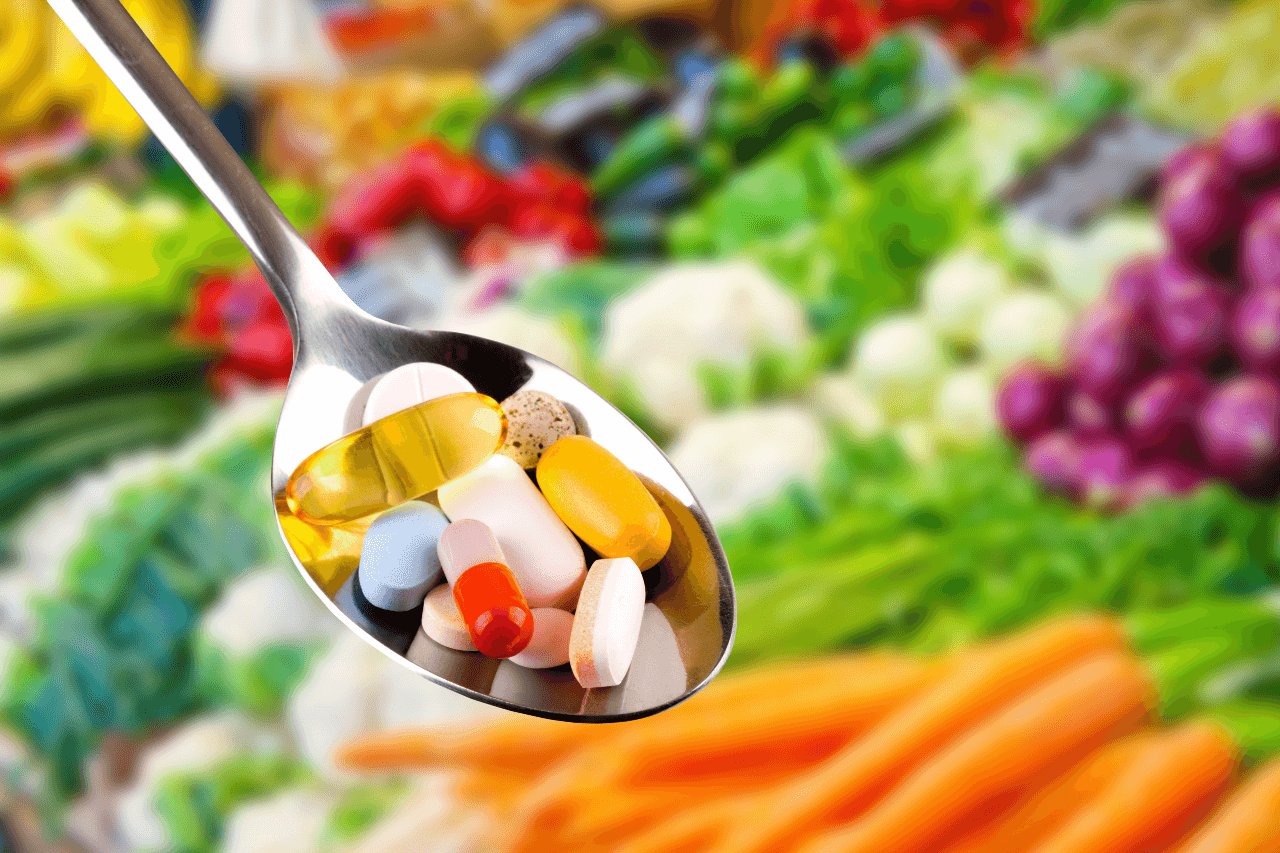 spoon with pills dietary supplements on vegetable background