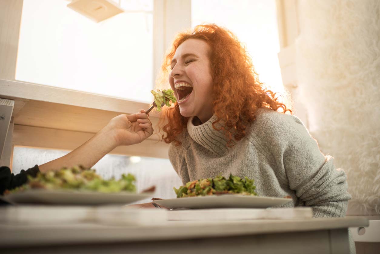 Woman being fed forkful of salad greens