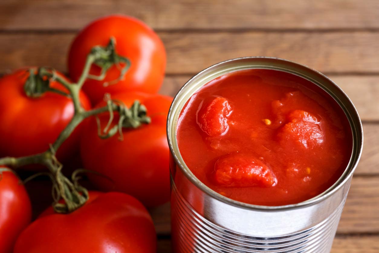 canned tomato next to tomatoes on the vine