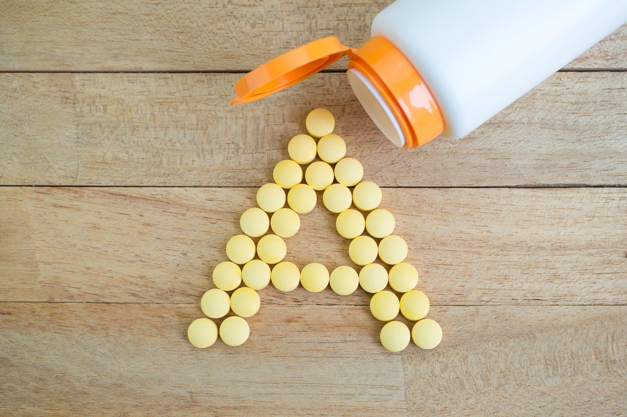 Yellow pills forming shape to A alphabet on wood background