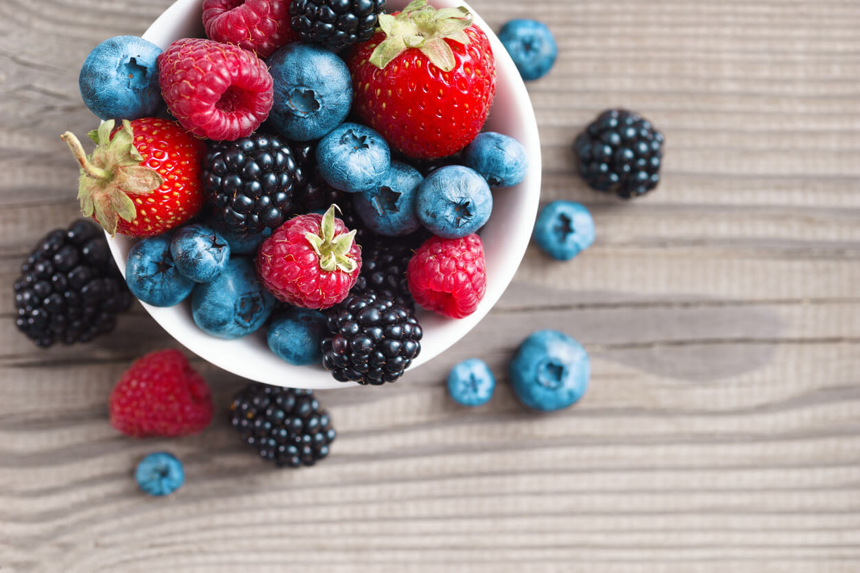 fresh berries in a basket on rustic wooden background