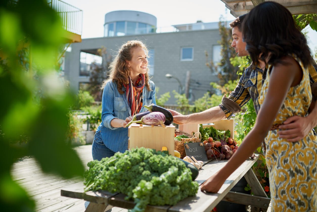 friendly woman tending an organic vegetable stall at farmer