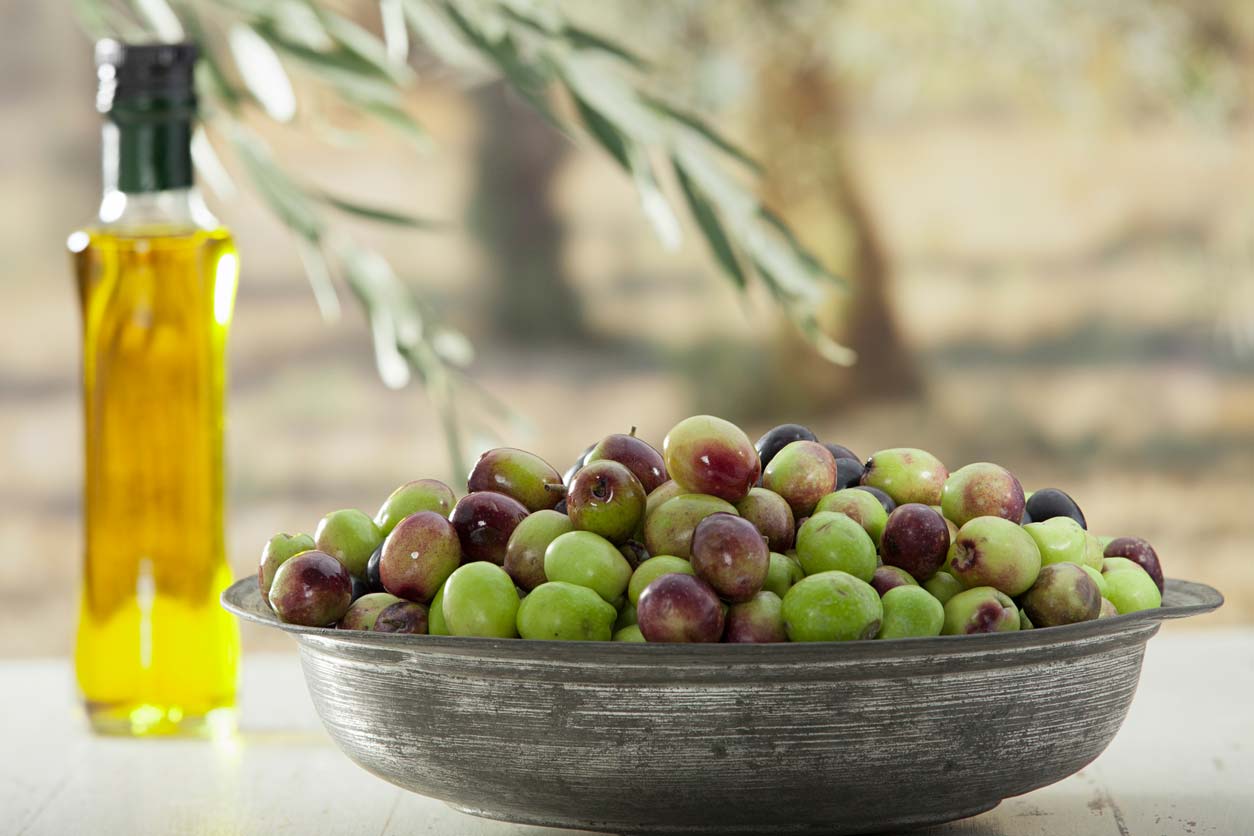 Raw olives and a jar of olive oil