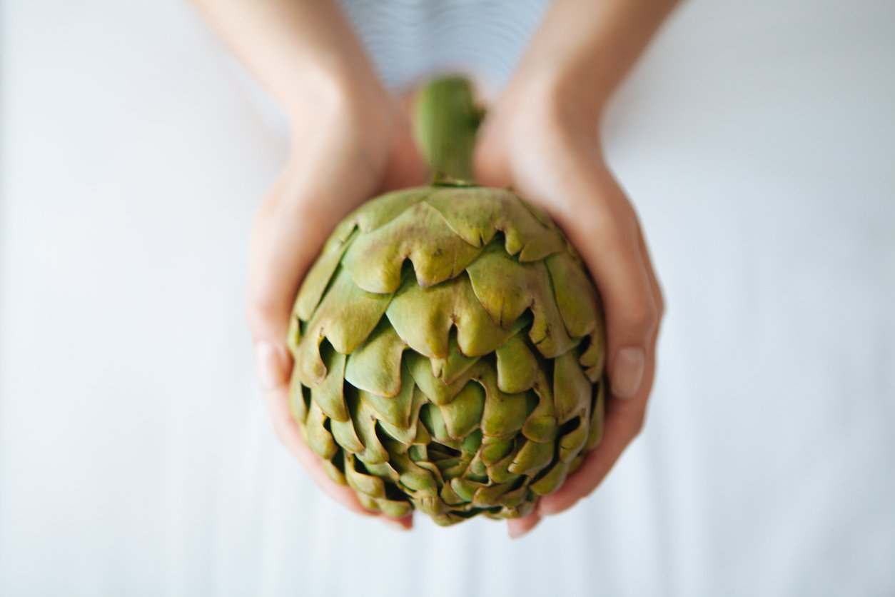 woman holding an artichoke