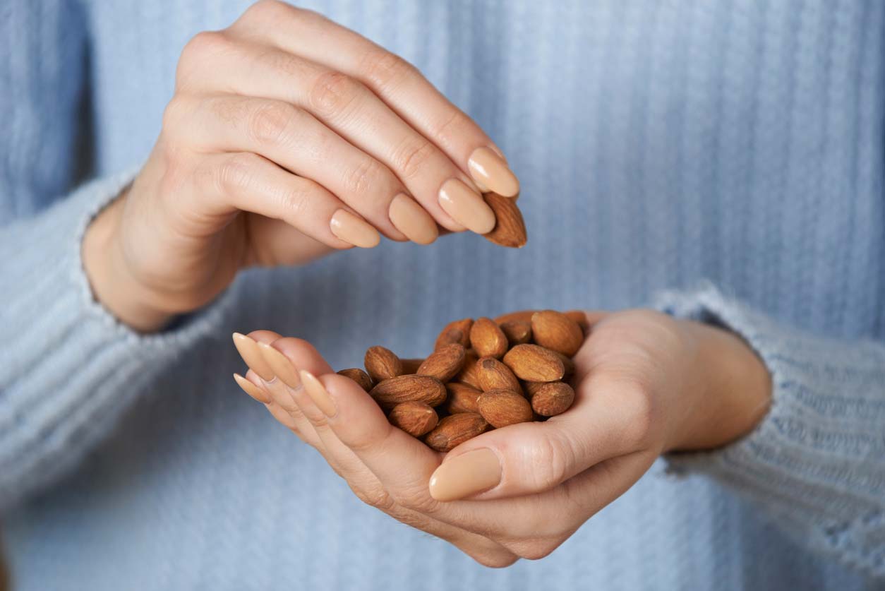 closeup of hands holding almonds which contain oxalates