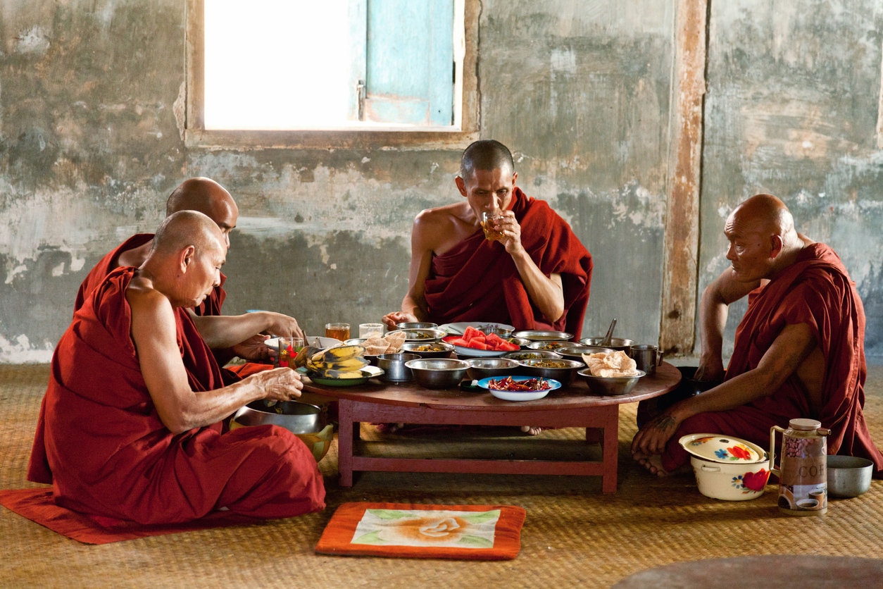 Heho, Myanmar - March 01, 2011 - Group of moniks in red robes eating lunch on the ground