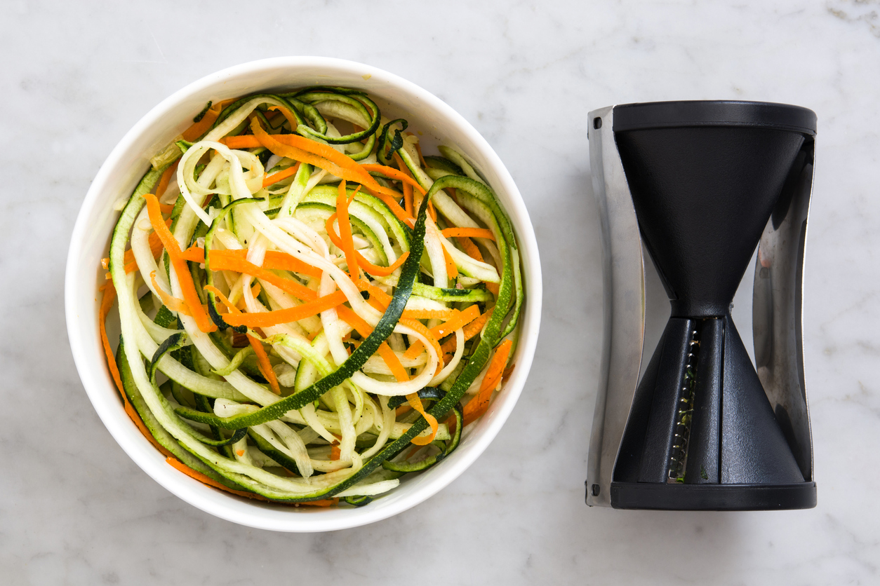 Zucchini and carrot noodles in a bowl, on marble background