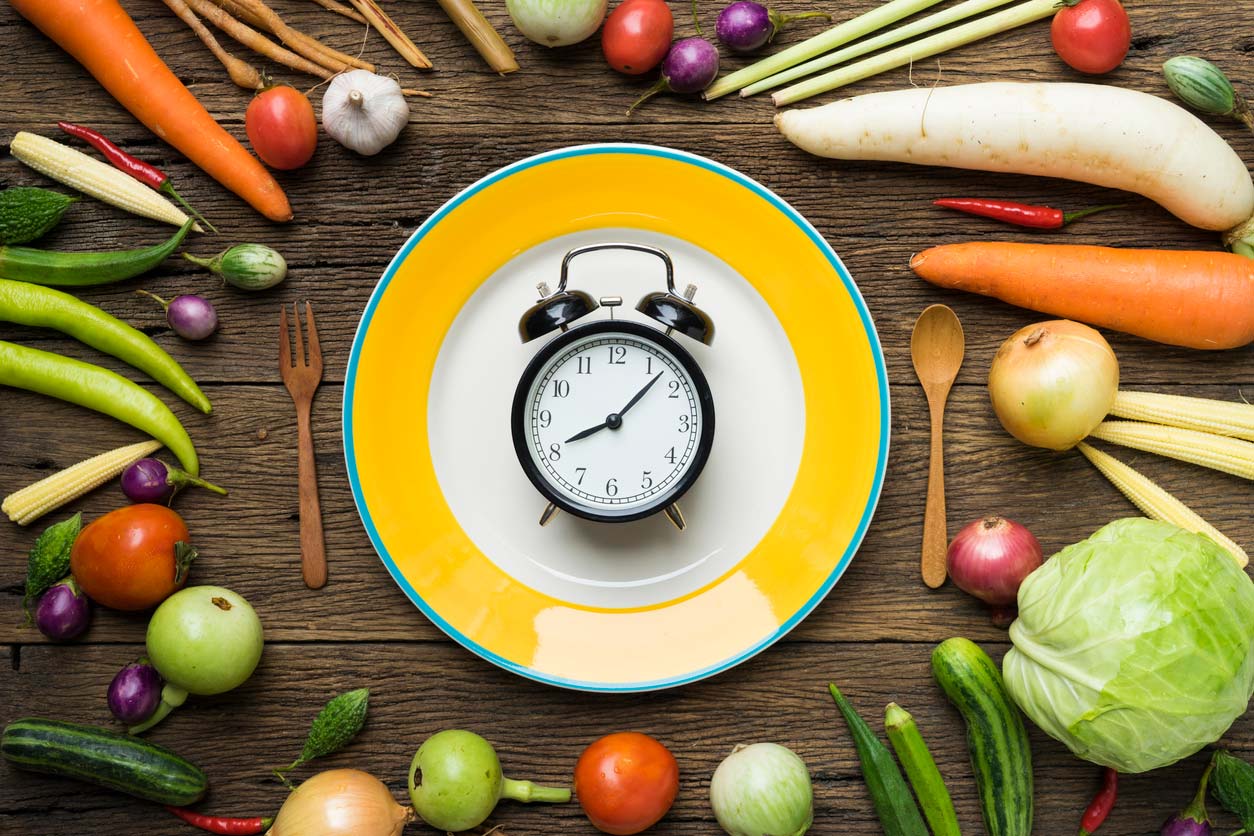 Vegetables surrounding plate with alarm clock