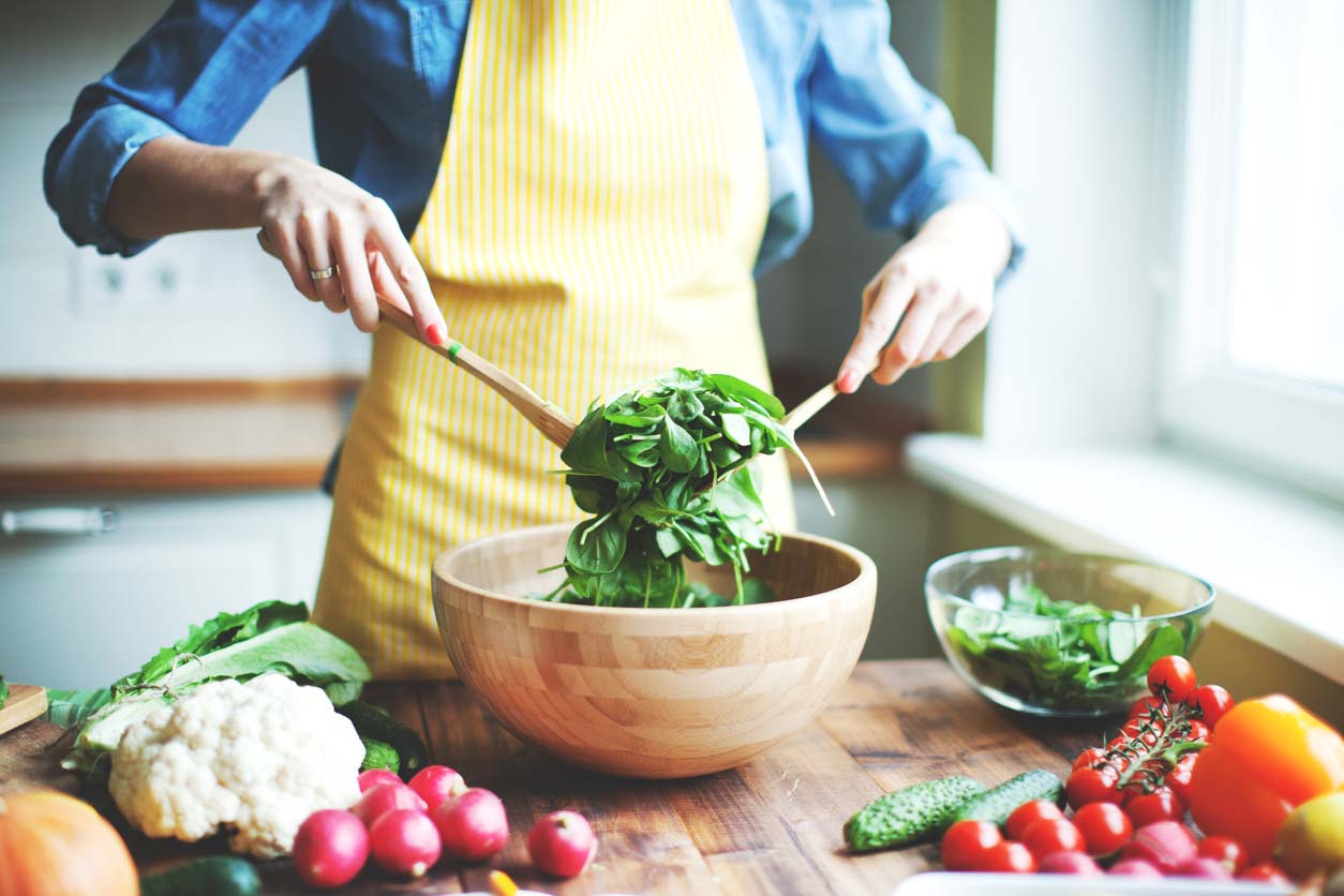 Person preparing a leafy green spinach salad