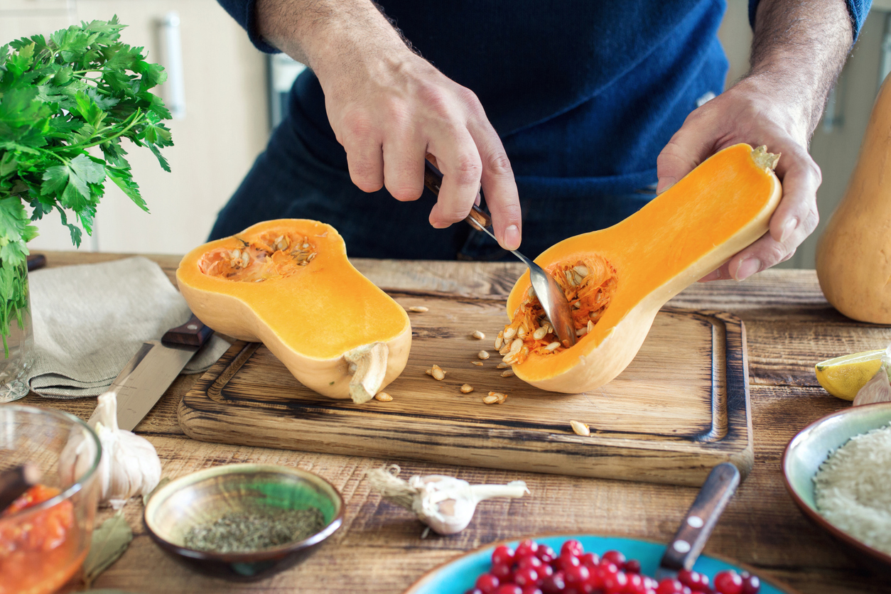 Man preparing healthy food of a pumpkin on a wooden table in a home kitchen