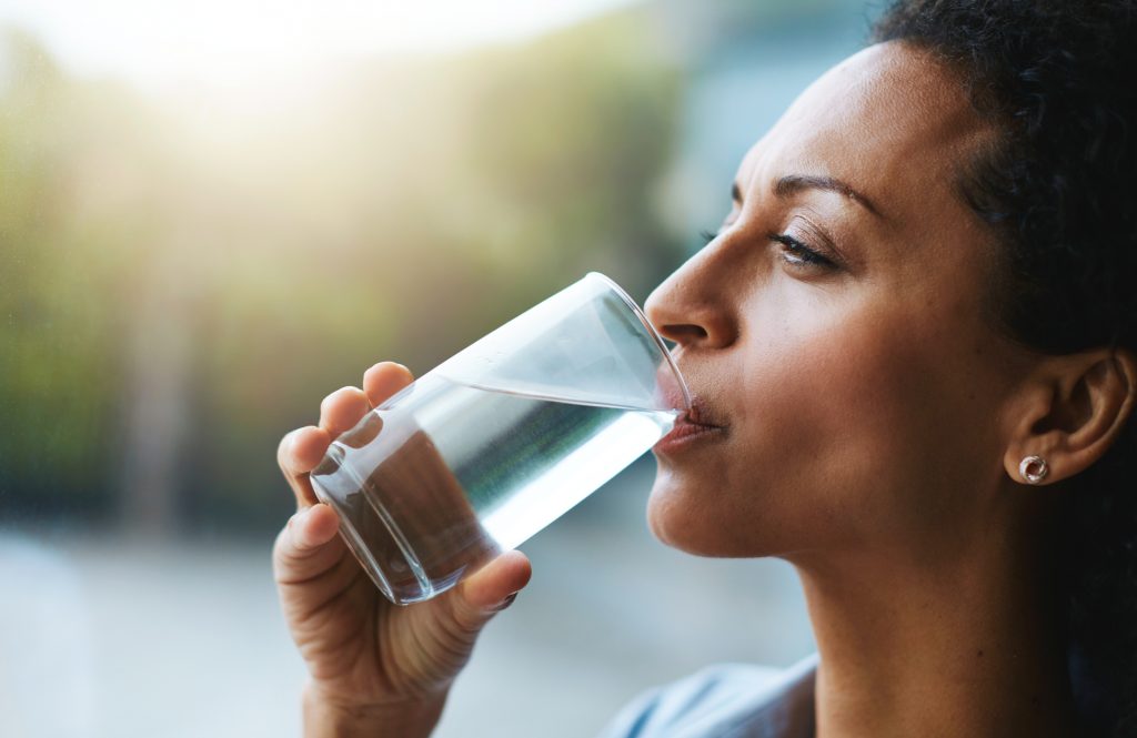 Woman drinking a glass of water - one of the the healthiest beverages