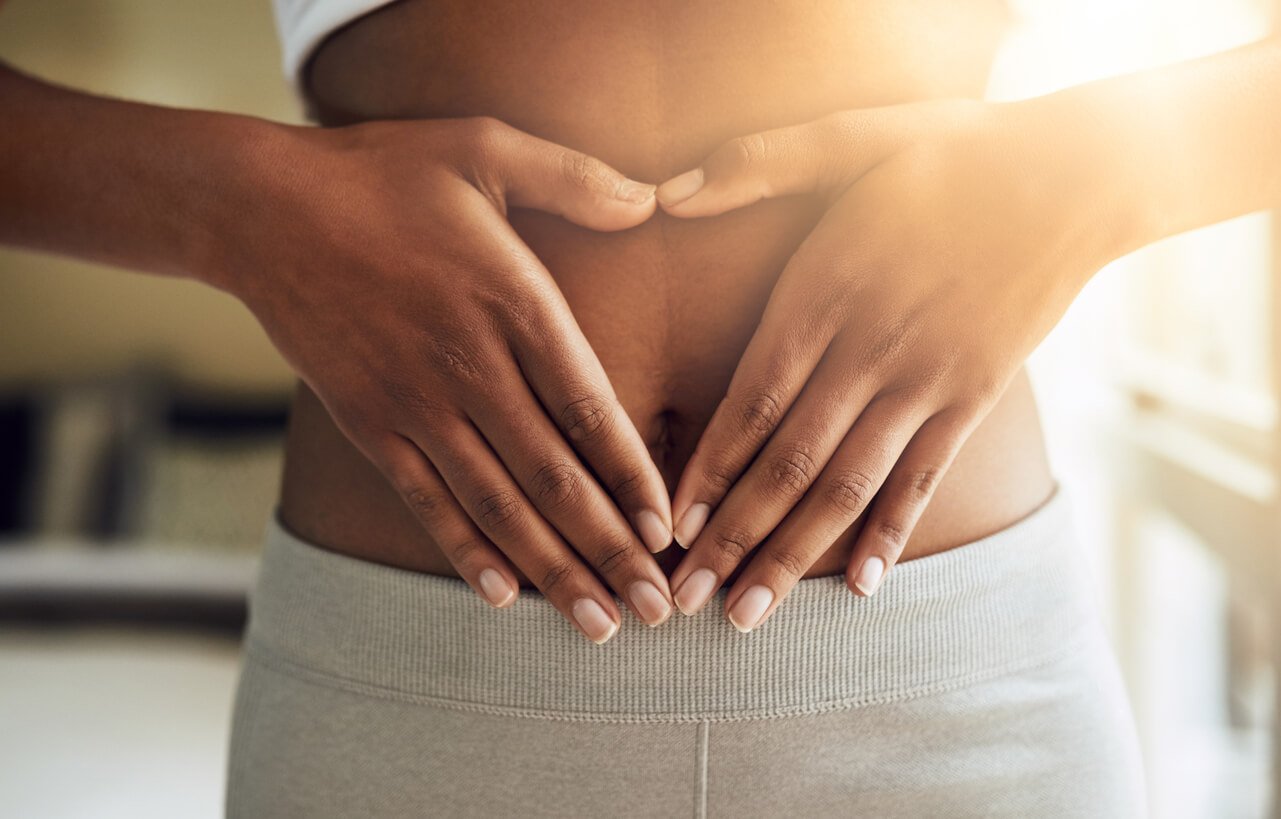 Fingers in shape of heart over belly