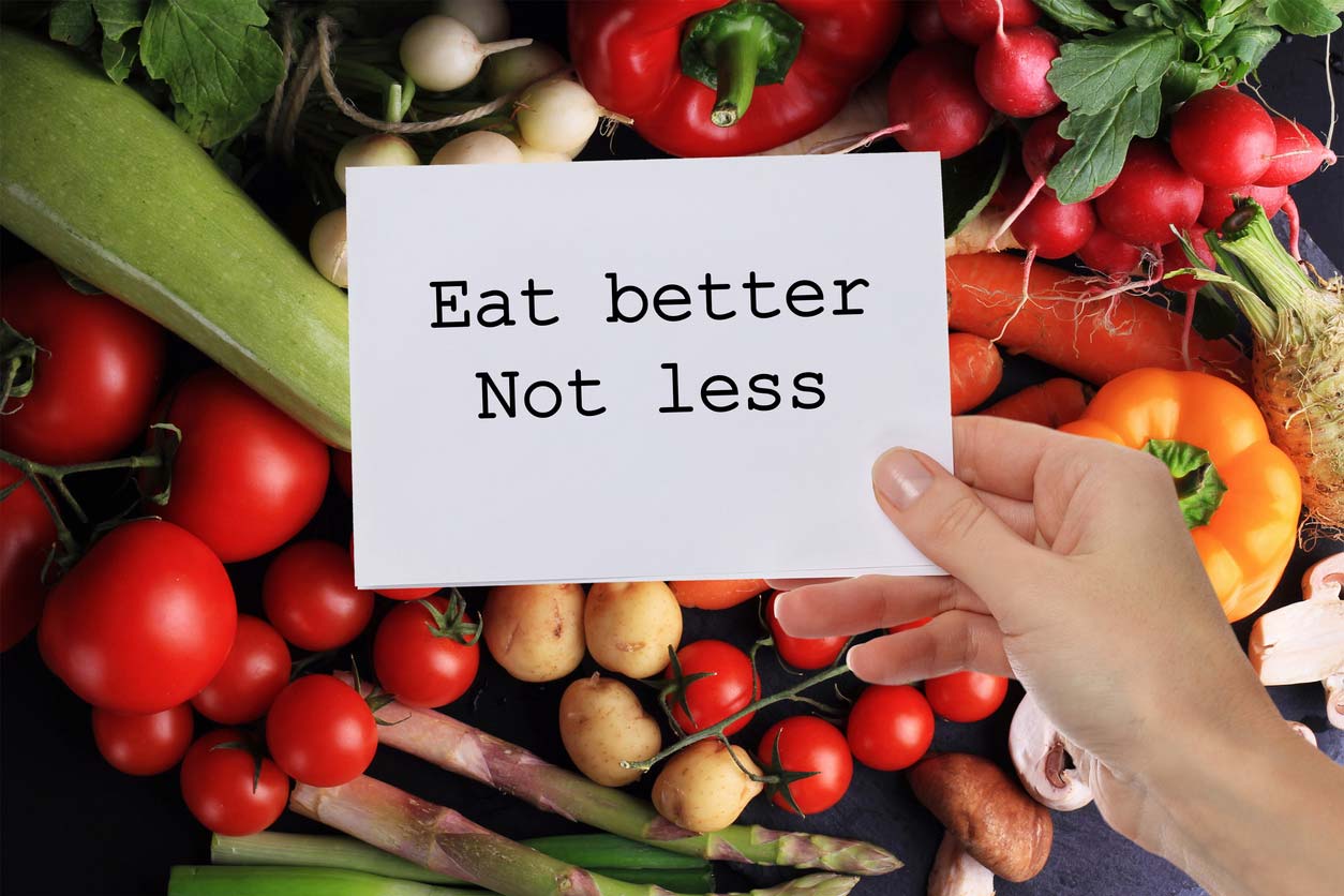 eat better not less inspirational note in front of vegetables