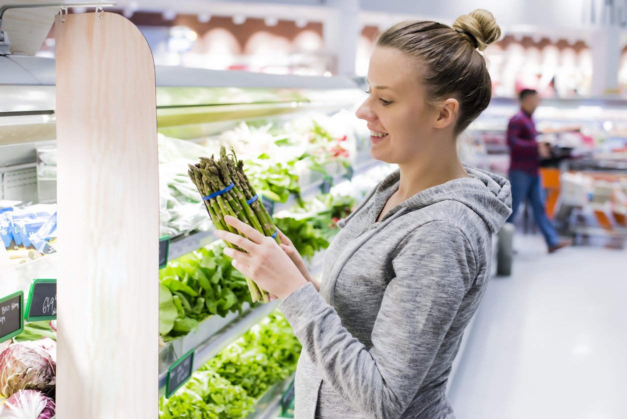 Happy Pregnant woman customer Buying asparagus at the supermarket, Young healthy female with fresh organic vegetable, Market stall with variety of Groceries