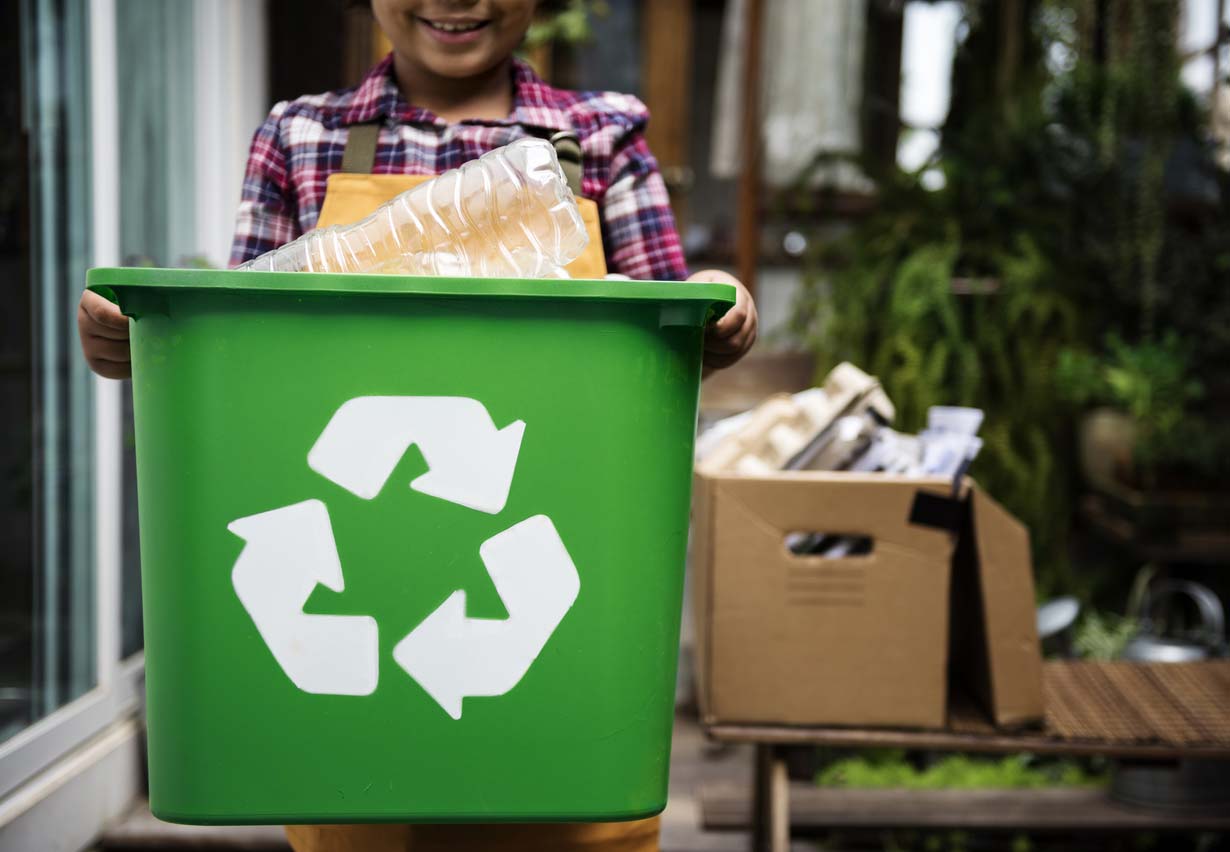 child carrying recycling box of plastic bottles