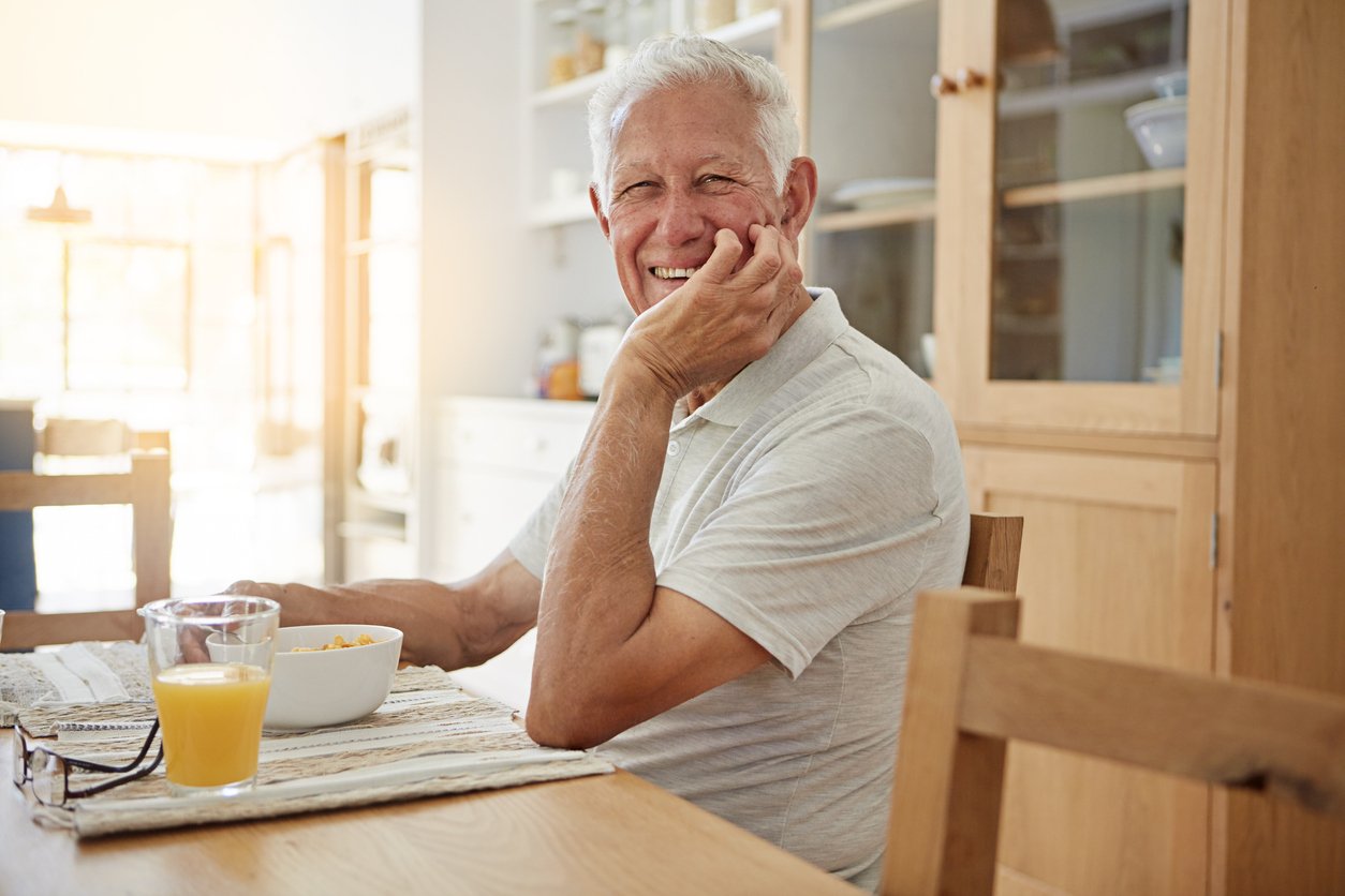 Portrait of a happy senior man having breakfast in his kitchen at home