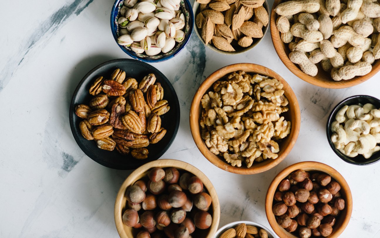 Assorted nuts in bowls on marble table, walnut, almond, hazelnut and other nuts