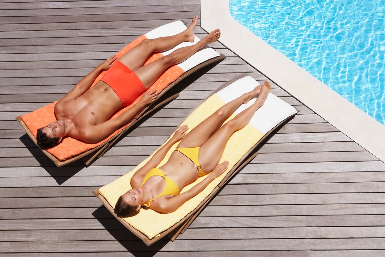 man and woman sunbathing on pool deck