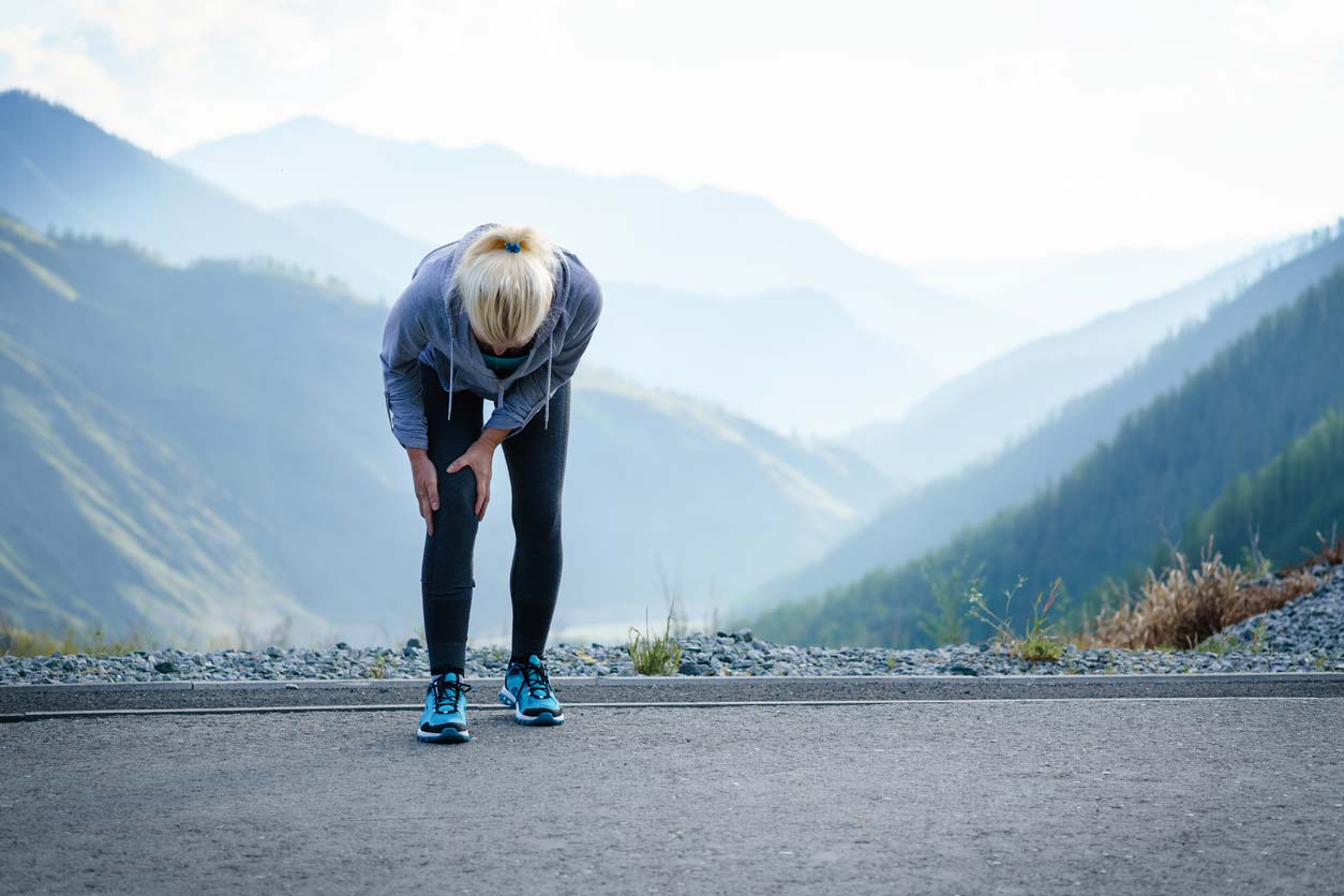 elderly woman runner tending to knee