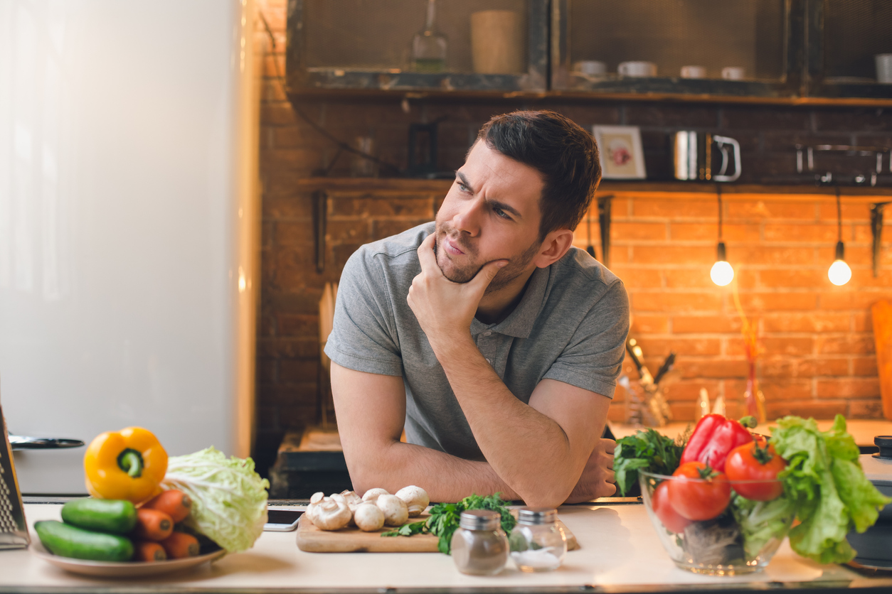 Young man vegan cooking healthy vegetable salad for dinner