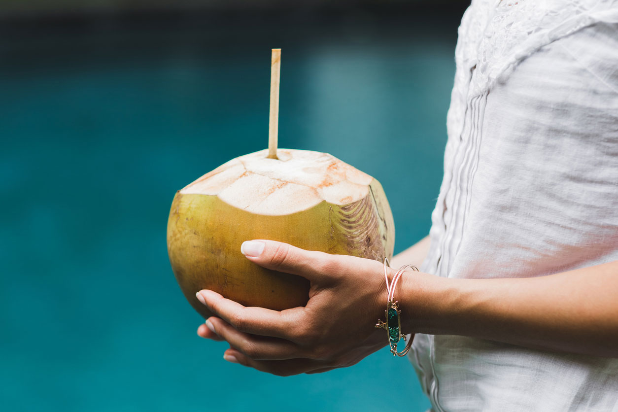 hands holding coconut with straw